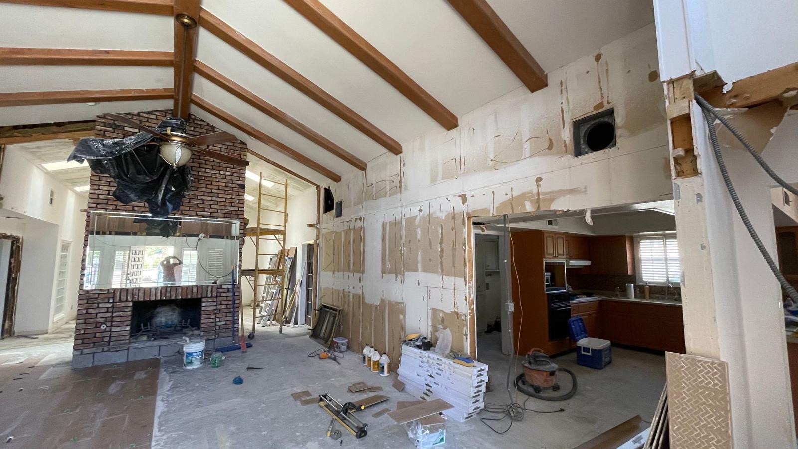 Interior renovation in progress with exposed beams and brick fireplace