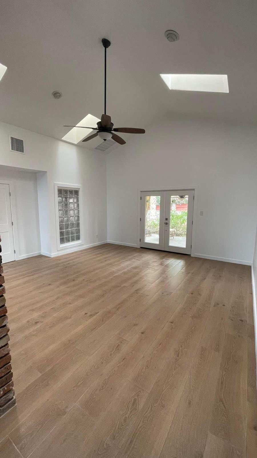 Bright renovated living room with vaulted ceiling, skylights, and new hardwood floors
